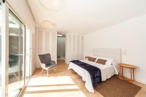 a white bedroom with a bed and a chair at Luxury Casa El Marques in Puerto del Carmen