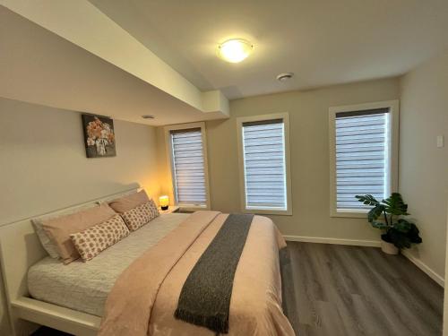 a bedroom with a bed and three windows at Cozy Private 1 bedroom basement suite - free parking and free Wifi in Winnipeg