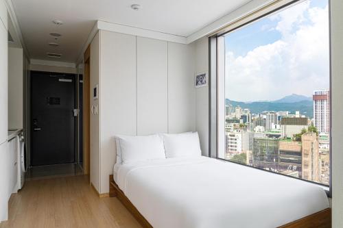 a white bed in a room with a large window at Urbanstay Myeongdong in Seoul