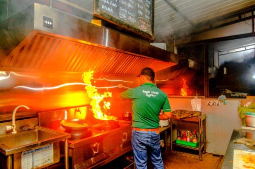 a man in a kitchen preparing food in a kitchen at Kutumbaya in Anuradhapura