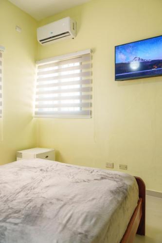 a bedroom with a bed and a tv on the wall at Hotel La Casona MC in La Romana