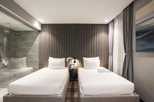two beds in a hotel room with a mirror at Grand Ocean Luxury Boutique - Infinity Rooftop Pool in Da Nang