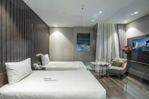 a hotel room with two beds and a glass table at Grand Ocean Luxury Boutique - Infinity Rooftop Pool in Da Nang