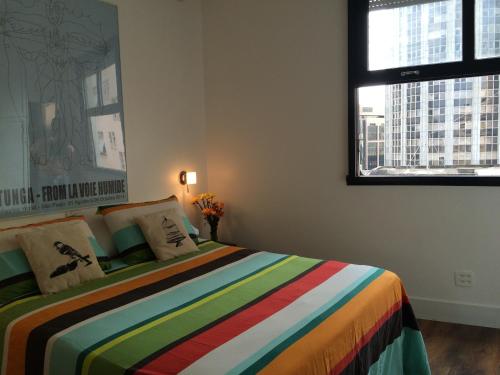 a bedroom with a colorful bed with two windows at Studio Rio Beira Mar in Rio de Janeiro