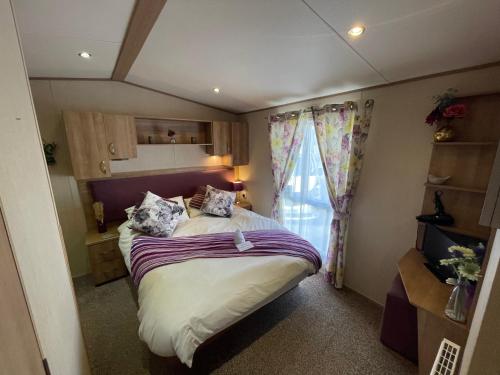 a small bedroom with a bed and a window at Lakeside Retreat 2 with hot tub, private fishing peg situated at Tattershall Lakes Country Park in Tattershall