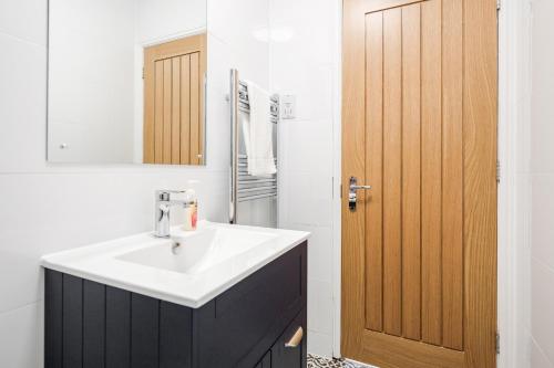 a bathroom with a sink and a wooden door at Comfortable 2BR Apartment in Bedford in Bedford