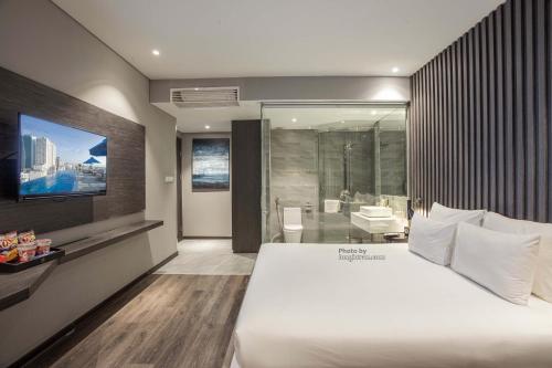 a bedroom with a large white bed and a bathroom at Grand Ocean Luxury Boutique - Infinity Rooftop Pool in Da Nang