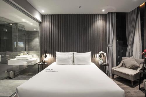 a bedroom with a large white bed and a bathroom at Grand Ocean Luxury Boutique - Infinity Rooftop Pool in Da Nang