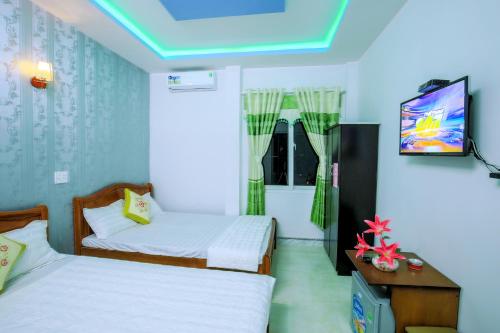 a room with two beds and a flat screen tv at Phuc Hau Hotel - Ly Son in Ly Son