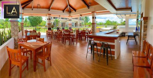 un restaurante con mesas y sillas de madera y un bar en La Candura, en Siquijor