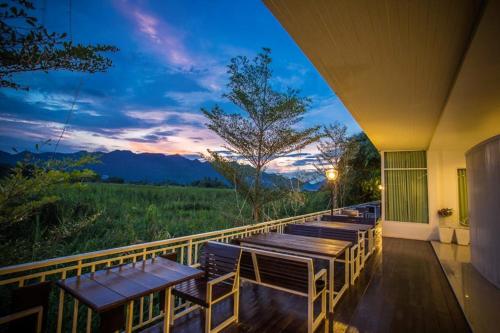 a row of tables and chairs on a balcony with a sunset at The Vista Pool Villa in Kanchanaburi