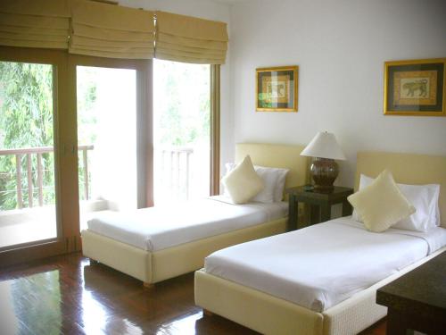 a hotel room with two beds and a balcony at Blue Canyon Country Club in Mai Khao Beach
