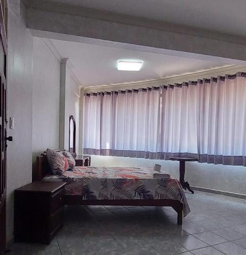 1 dormitorio con cama, mesa y cortinas en Hotel Florio, en Santa Cruz de la Sierra