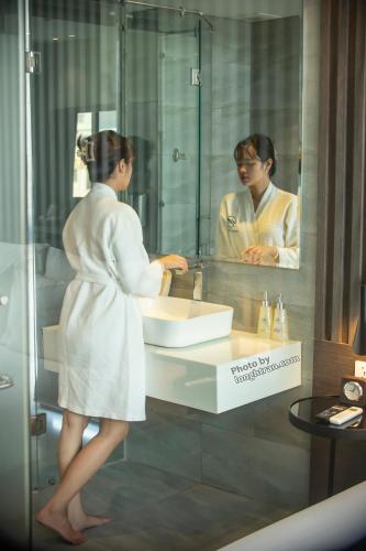 a woman standing in front of a sink in a bathroom at Grand Ocean Luxury Boutique - Infinity Rooftop Pool in Da Nang