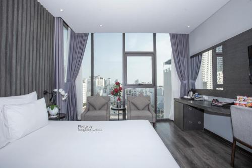 a hotel room with a bed and a desk and window at Grand Ocean Luxury Boutique - Infinity Rooftop Pool in Da Nang