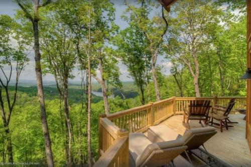 a wooden deck with chairs and a view of the woods at Sky High Lodge - Blue Ridge in Blue Ridge