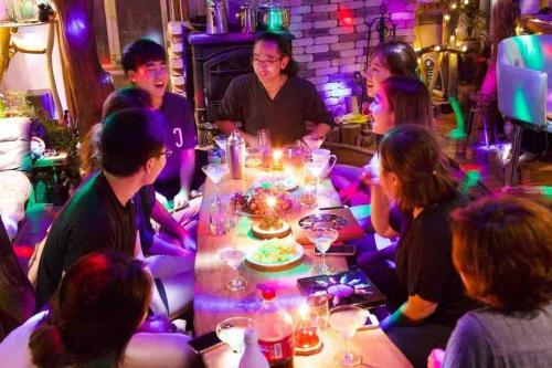 un grupo de personas sentadas alrededor de una mesa en un club en Mizuno Sang's Tree House, 