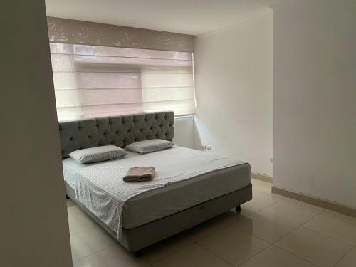 1 cama en un dormitorio blanco con ventana en Departamento , Infinity Host, en Guayaquil