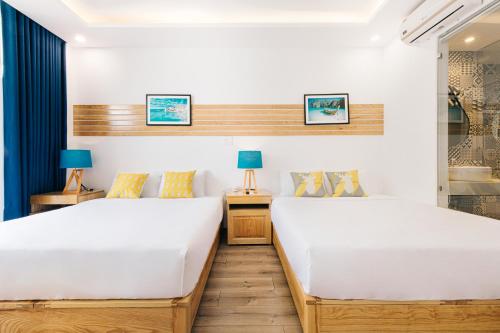 2 camas en una habitación de hotel con 2 lámparas en La Maison De Fleurs, en Da Nang