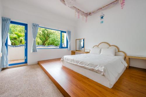 a white bedroom with a large bed and a window at White Lighthouse in Xiaoliuqiu