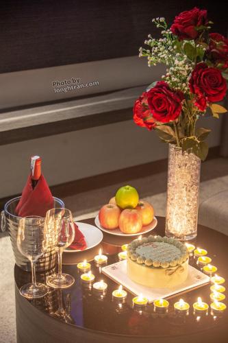 a table with candles and a cake and a vase with roses at Grand Ocean Luxury Boutique - Infinity Rooftop Pool in Da Nang