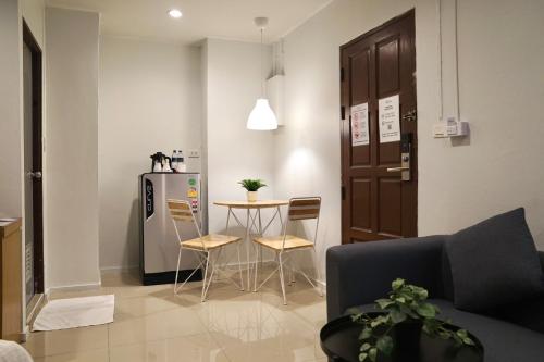 a living room with a table and a refrigerator at The View Residence in Bangkok