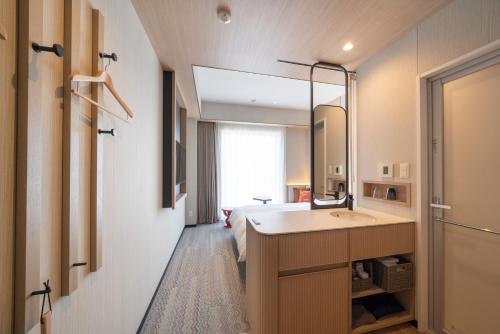 a bathroom with a bed and a sink and a mirror at HOTEL &mu; STYLE INUYAMA experience in Inuyama