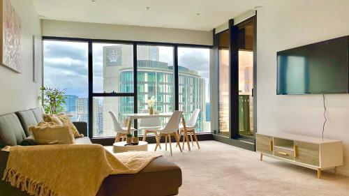 a living room with a table and a large window at Prima Tower Apartment Face to Crown by GoodLive in Melbourne