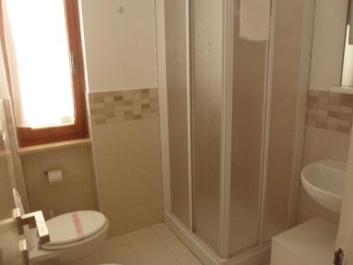 a bathroom with a shower and a toilet and a sink at Hotel Villa Rosa in Porto Azzurro