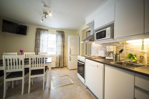 ロヴァニエミにあるHotel Aakenus Holiday Home Kymppiのキッチン(白い家電製品、テーブル、椅子付)