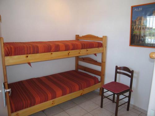 1 Schlafzimmer mit 2 Etagenbetten und einem Stuhl in der Unterkunft Appartement Saint-Cyprien, 3 pièces, 6 personnes - FR-1-106-59 in Saint-Cyprien