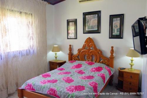 Un dormitorio con una cama con flores rosas. en Casa ÍSIS de aluguel por temporada em Capão da Canoa com piscina en Capão da Canoa