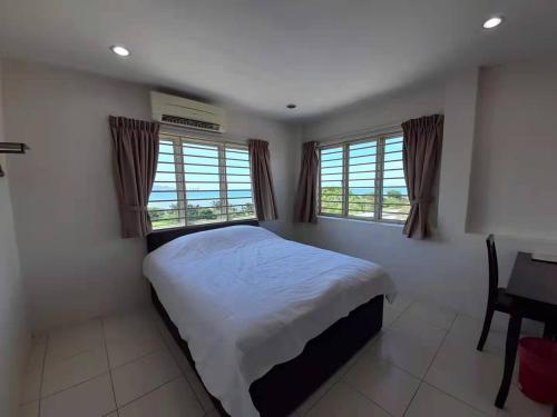 a bedroom with a bed and a desk and two windows at Zing Motel in Butterworth
