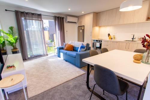 uma cozinha e sala de estar com uma mesa e um sofá azul em Luxurious inner city 2 bed pad em Christchurch