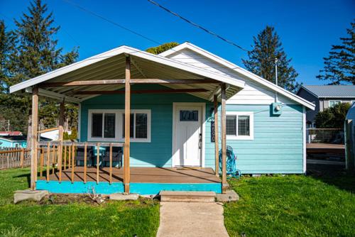 una pequeña casa azul con un porche en un patio en Finding Nevør-land, en Netarts