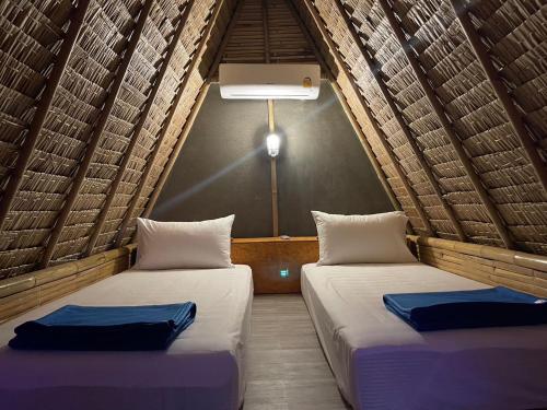 2 bedden in een kamer met rieten dak en 3 stoelen. bij Slumber Resort Koh Chang in Trat