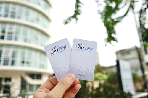 a hand holding up two tickets in front of a building at The View Residence in Bangkok