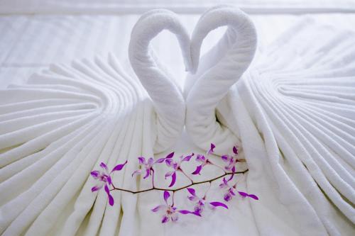 two swans shaped like hearts on a bed with purple flowers at Anh Thảo Hotel Quy Nhơn in Quy Nhon