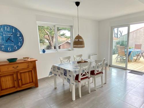 une salle à manger avec une table, des chaises et une horloge dans l'établissement Maison Rénovée: 300m de la Mer, Terrasse, Jardin, WIFI, Animaux Ok - FR-1-231-281, à Bretignolles-sur-Mer