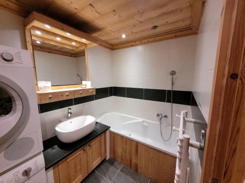 a bathroom with a tub and a sink and a washing machine at Appartement spacieux 4 pièces, 3 ch., parking et WiFi, centre des Gets - FR-1-598-126 in Les Gets
