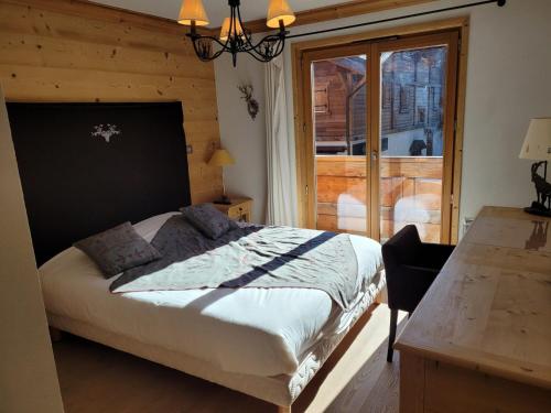 a bedroom with a bed and a table and a window at Appartement spacieux 4 pièces, 3 ch., parking et WiFi, centre des Gets - FR-1-598-126 in Les Gets