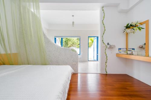 a bedroom with a white bed and a wooden floor at White Lighthouse in Xiaoliuqiu
