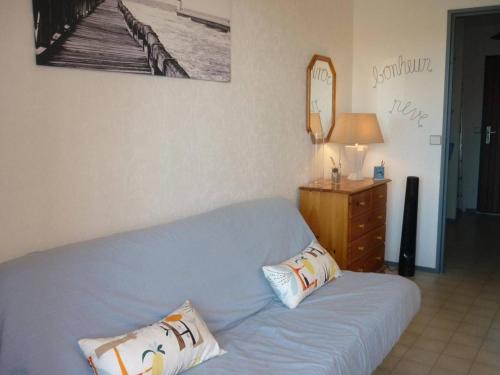 - un canapé bleu avec deux oreillers dans le salon dans l'établissement Appartement Charmant avec Piscine, Tennis et Parking à Capbreton, Proche Océan et Port de Plaisance - FR-1-239-880, à Capbreton