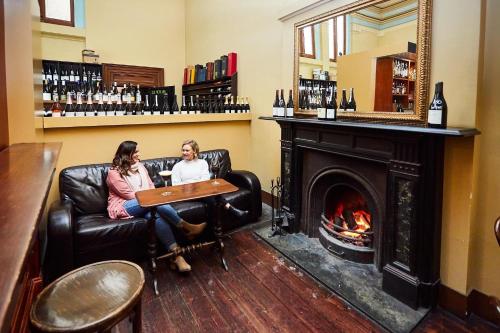 two women sitting in a bar with a fireplace at Allawah Bendigo in Bendigo