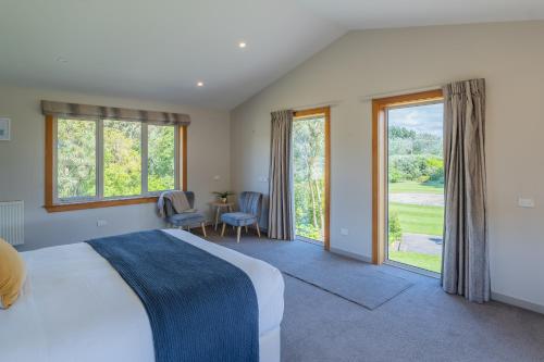 a bedroom with a bed and a view of a golf course at Anam Cara Gardens luxury Villa in Otaki
