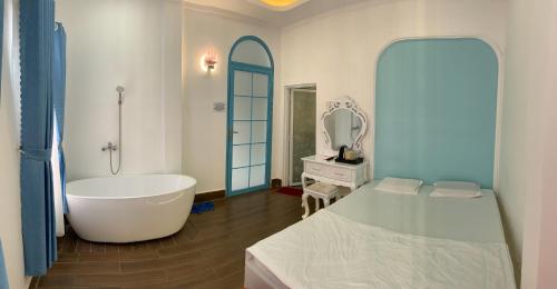 a bathroom with a tub and a bed and a mirror at Hotel MAI TUAN Nguyễn Văn Linh in Phú Khương