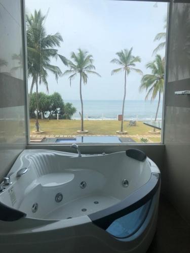a bath tub with a view of the beach at The Lighthouse Negombo in Negombo