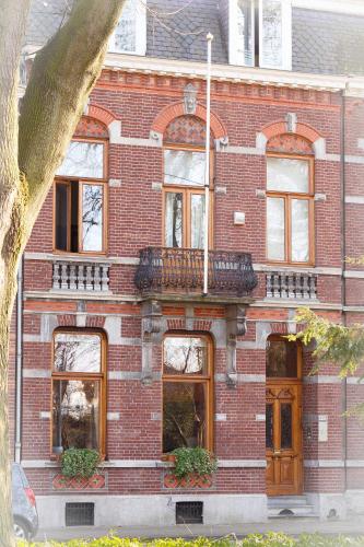 a red brick building with a balcony on it at Maison Au Parc in Maastricht