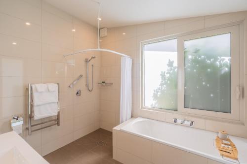 a white bathroom with a tub and a window at Anam Cara Gardens luxury Villa in Otaki
