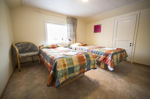 a bedroom with two beds and a chair and a window at Hotel Aakenus Holiday Home Kymppi in Rovaniemi